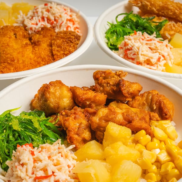 Three bowls of food, each with fried chicken or fish, seaweed, crab salad, corn, and pineapple.