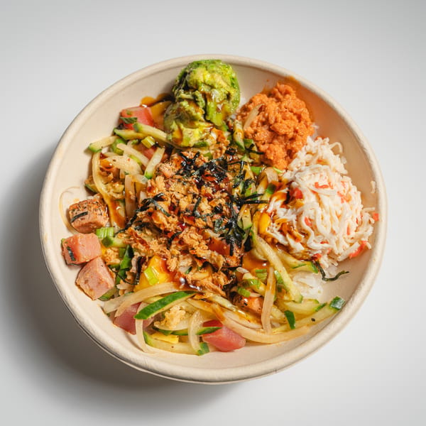 A colorful poke bowl with tuna, salmon, avocado, crab salad, and various vegetables.